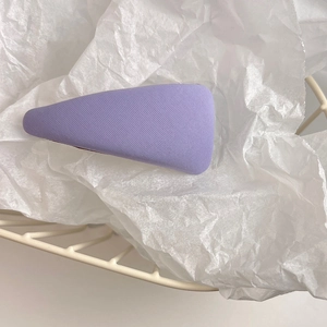 Close-up of a purple fabric hair clip with a diagonal twill texture on a clean white backdrop