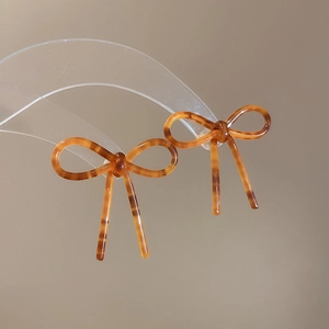 Gros plan de boucles d'oreilles nœud en acétate écaille avec texture résine ambre