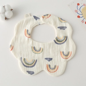 Detail of 100% cotton gauze baby bib with rainbow cloud patterns and soft texture