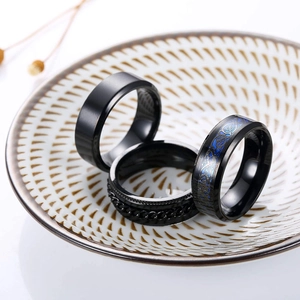 Detailed view of three black titanium rings featuring chain inlay and celtic dragon patterns