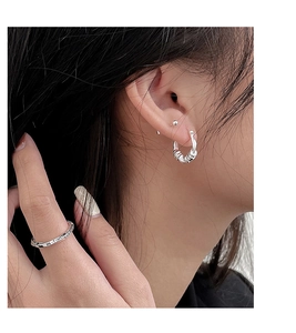 Close-up of S925 sterling silver geometric hoop earrings and thin band ring on a model
