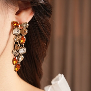Macro shot of vintage style gold drop earrings with amber and brown rhinestones