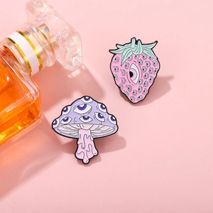 Pink surrealist enamel pins set featuring strawberry and mushroom with eyeball patterns