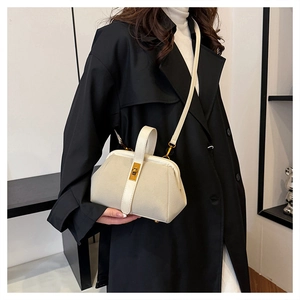 Close-up of retro shell-shaped handbag with golden rectangular clasp and leather trim