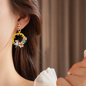 Détail de boucles d'oreilles vintage avec anneaux en émail jaune et motifs de lapins
