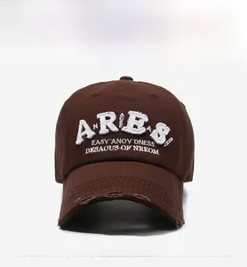 Close-up of white 3D embroidery and distressed ripped details on a vintage brown cap