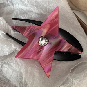 Macro detail of star-shaped pink marble acetate hair claw with a heart rhinestone