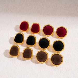 Macro shot of velvet geometric earrings in red, black, and brown with gold trim edges