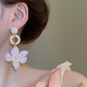 Detail von rosa Marmor-Blumen-Ohrring mit goldenem Metallring am Modelohr