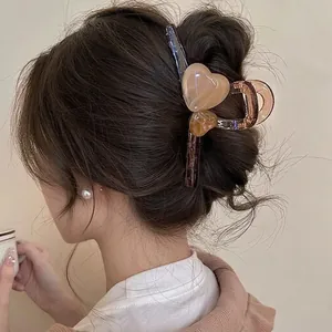 Large matte acrylic shark hair claw clip with heart accents on model's hair