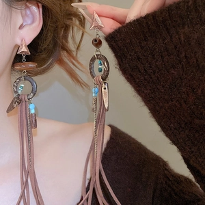 Detail of bohemian tassel earrings with wooden beads and blue accents on a model