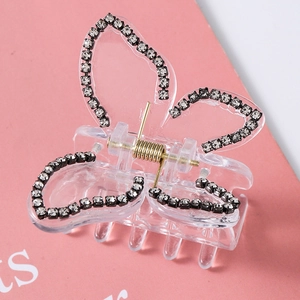 Detail shot of a clear butterfly hair claw clip with black rhinestone edges and gold spring