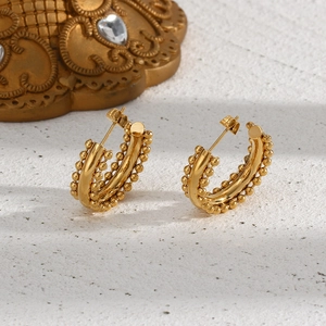 Detailed macro view of 18K gold plated C-shaped hoop earrings with beaded textured edges