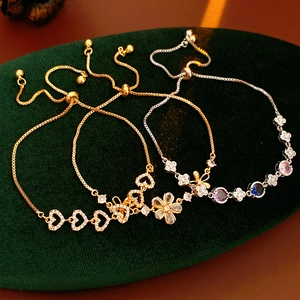 Vue détaillée de trois breloques fleurs et cœurs en zircon sur des bracelets réglables