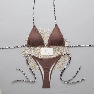 Detail of dark brown bikini with leopard print ties on a decorative gold sun coaster