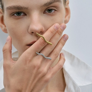 Detail showing minimalist 18k gold and silver wavy rings worn on fingers