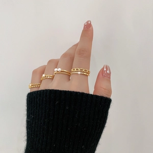 Detail of four gold layered rings with star rhinestones and pearls on model's hand