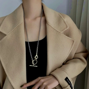 Close-up of a silver OT buckle necklace worn over a khaki coat for a punk look