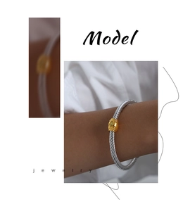 Detailed view of dual-tone cable twist bangle featuring a yellow marquise-cut zircon stone
