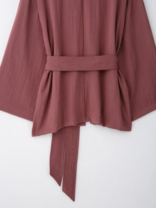 Detail view of pink linen kimono wrap top showing waist belt and fabric texture