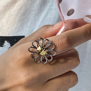Close-up of a daisy ring in silver and gold steel worn on a finger for a stylish look