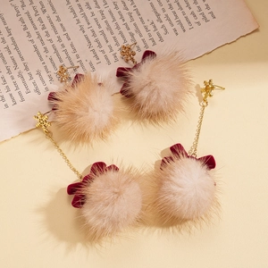 Vintage style bow and snowball earrings with golden snowflakes on retro newspaper background