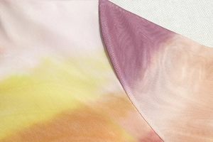 Detail-Makroaufnahme von Batik-Mesh-Stoff mit Nähten und warmen Farbverläufen