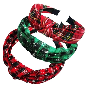 Detailed view of three festive plaid knotted headbands in red and green holiday patterns