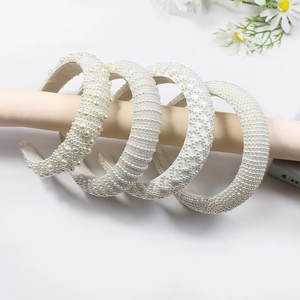 Elegant white pearl headbands set with multiple bead designs on a beige display stand
