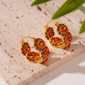 Detailed macro view of vintage orange rose earrings with brown crystals on stone background
