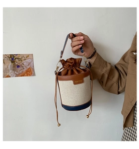 Detailed close-up of canvas bucket bag with leather drawstring and metal hardware