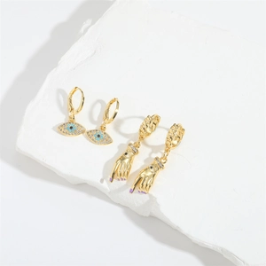 Golden hand-shaped drop earrings and evil eye hoops with blue zircons on stone base