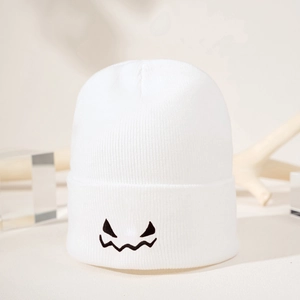 Detail of white knit beanie with black Halloween ghost face embroidery and folded brim