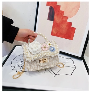 Detail of tweed girl's handbag with large white camellia, pearls and gold chain strap