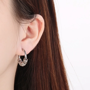Close-up of a silver hoop earring with an engraved bead charm worn by a male model