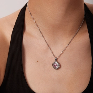 Detail view of square pink crystal pendant necklace with silver spiral frame on model