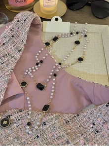Close-up of multilayer long pearl necklace with black gems on tweed fabric background