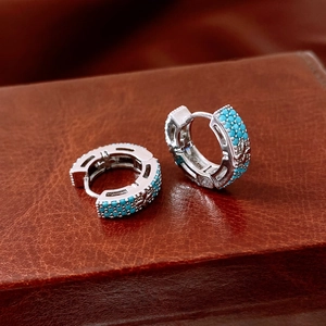 Gros plan de boucles d'oreilles argentées serties de pierres bleues sur cuir brun