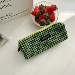 Detail of green houndstooth pencil case with yellow zipper and merciparis woven label