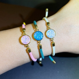 Close-up of woven braided rope bracelets with colorful sparkling round crystal pendants