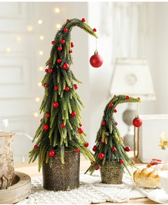 Detail of two mini artificial Christmas trees with red berries and golden textured pots