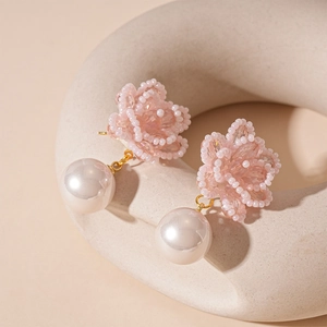 Detail of pink crystal flower earrings with hanging white pearls and golden hardware