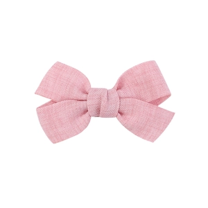 Detailed view of a handmade pink fabric bow hair clip with textured cotton linen finish