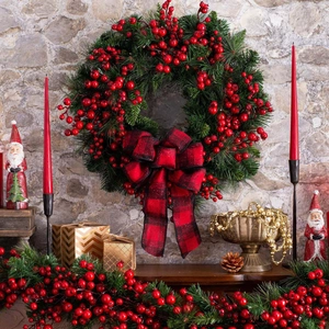 Christmas wreath with red berries and black-red buffalo plaid bow on stone wall