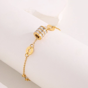 Detail shot of a gold stainless steel bracelet featuring a roman numeral charm and rhinestones