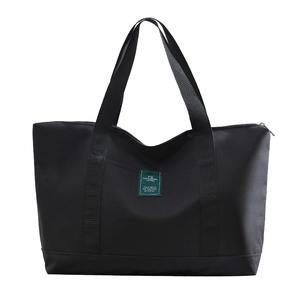 Large black canvas travel duffel bag with wide shoulder straps and green label detail