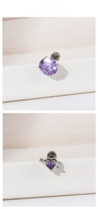 Detailed view of titanium steel ear studs with purple zircon heart and round stone shapes