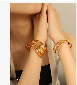 Detail view of gold titanium steel bracelets with elegant multi-layer wavy design on model wrist