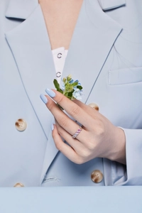 Detail of colorful gemstone eternity ring on model hand with blue floral accents