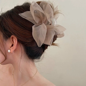 Close-up of elegant beige tulle double bow hair claw clip worn on a woman's hair